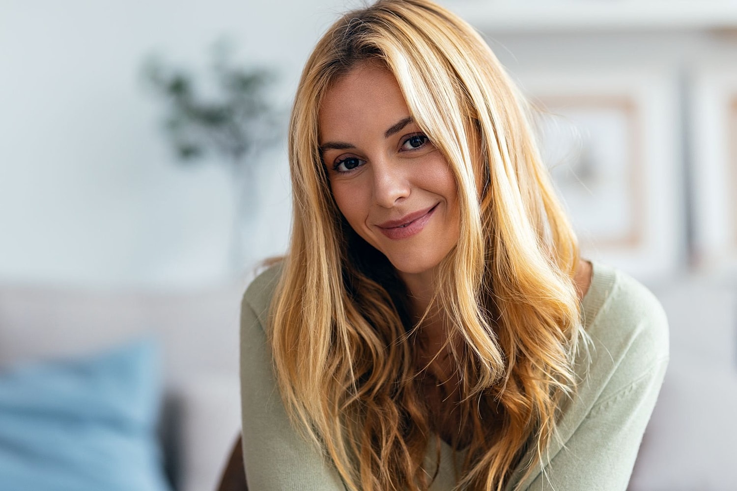 Smiling woman with long blonde hair indoors.