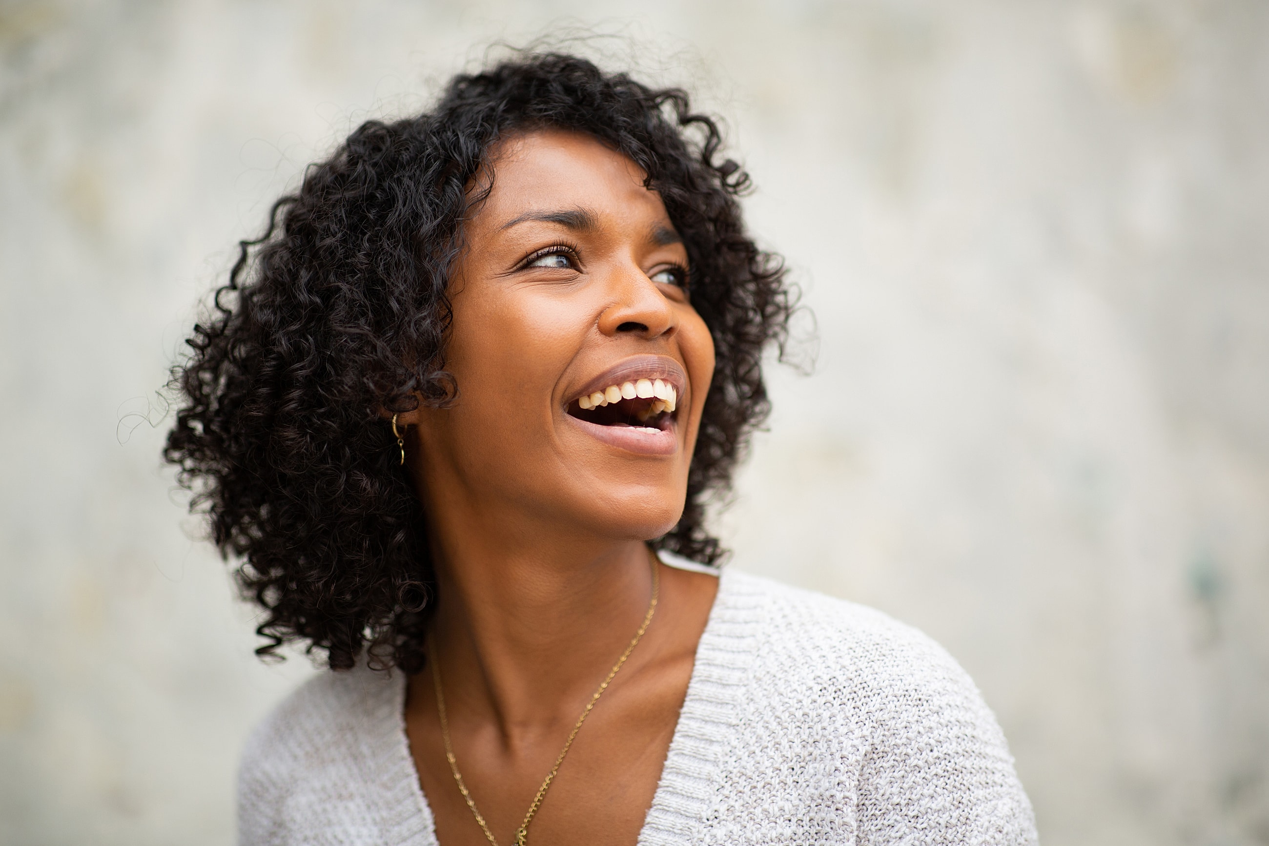 Smiling woman with curly hair and joyful expression.