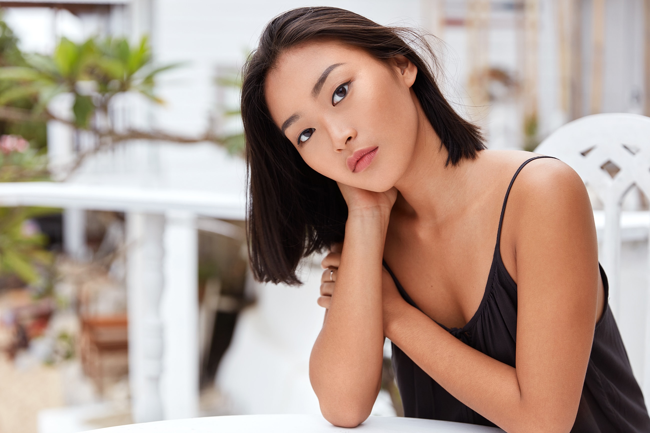 Woman posing thoughtfully at a table outdoors.